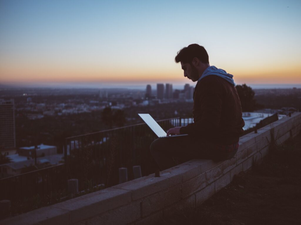 Man using laptop on edge of rooftop